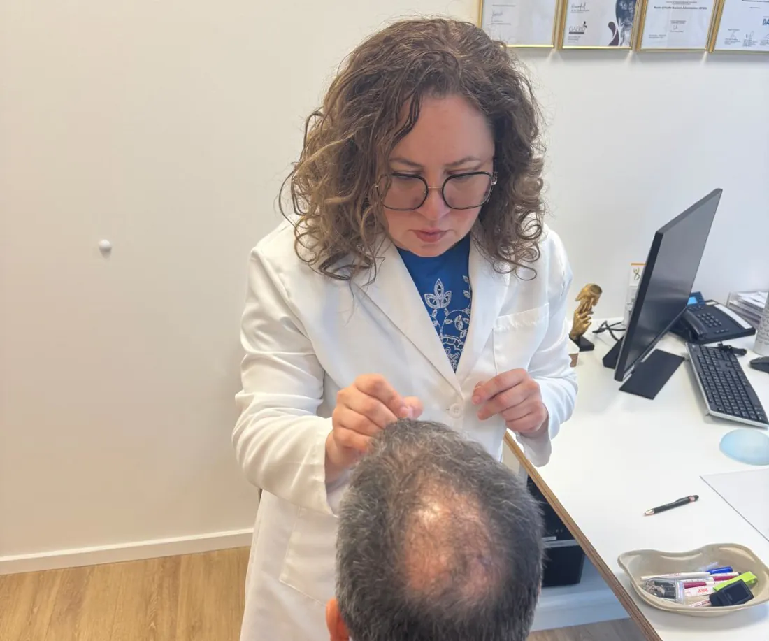 Dr. med. Gulshan Ahmadli untersucht die Kopfhaut eines Patienten in der Facharzt-Praxisklinik in Hannover